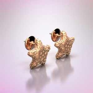 May include: A pair of gold-tone starfish stud earrings. The earrings have a detailed, textured design.