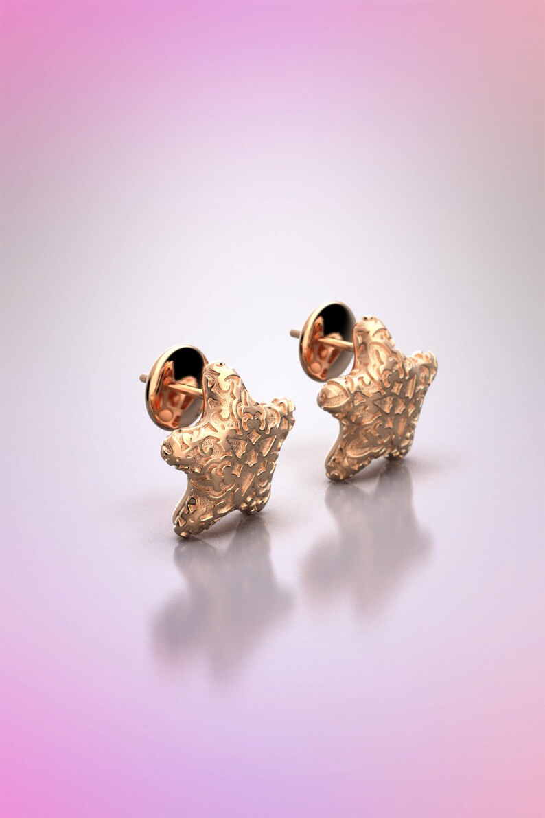 May include: A pair of gold-tone starfish stud earrings. The earrings have a detailed, textured design.
