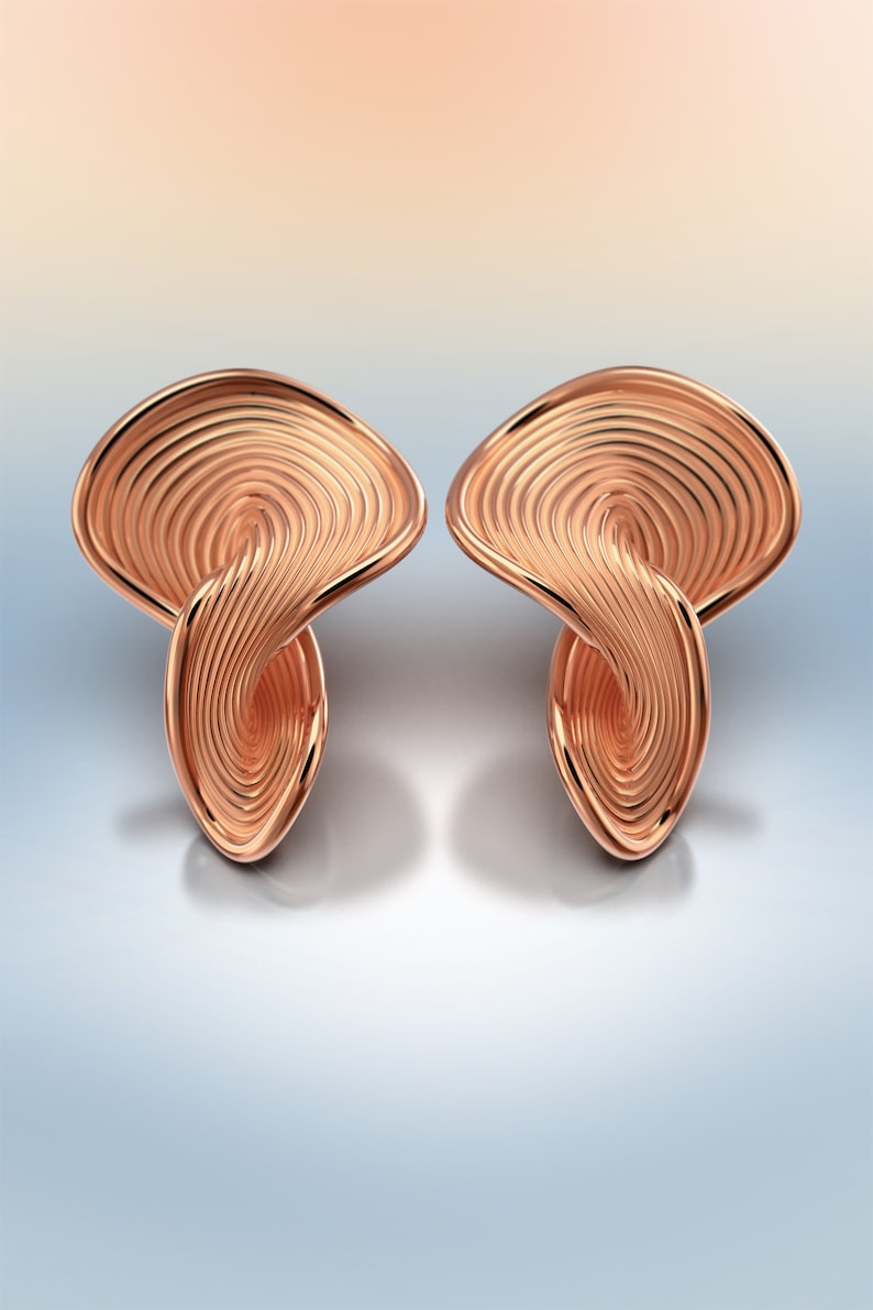 May include: A pair of rose gold earrings with a unique, swirling, abstract design.