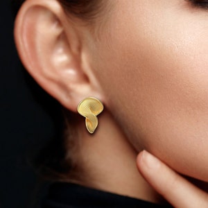 May include: Gold earrings with a swirling, textured design. The earrings are shaped like a teardrop.
