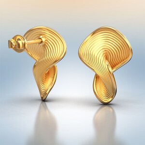 May include: A pair of gold-toned earrings with a twisted, wave-like design. The earrings have a smooth, polished finish.