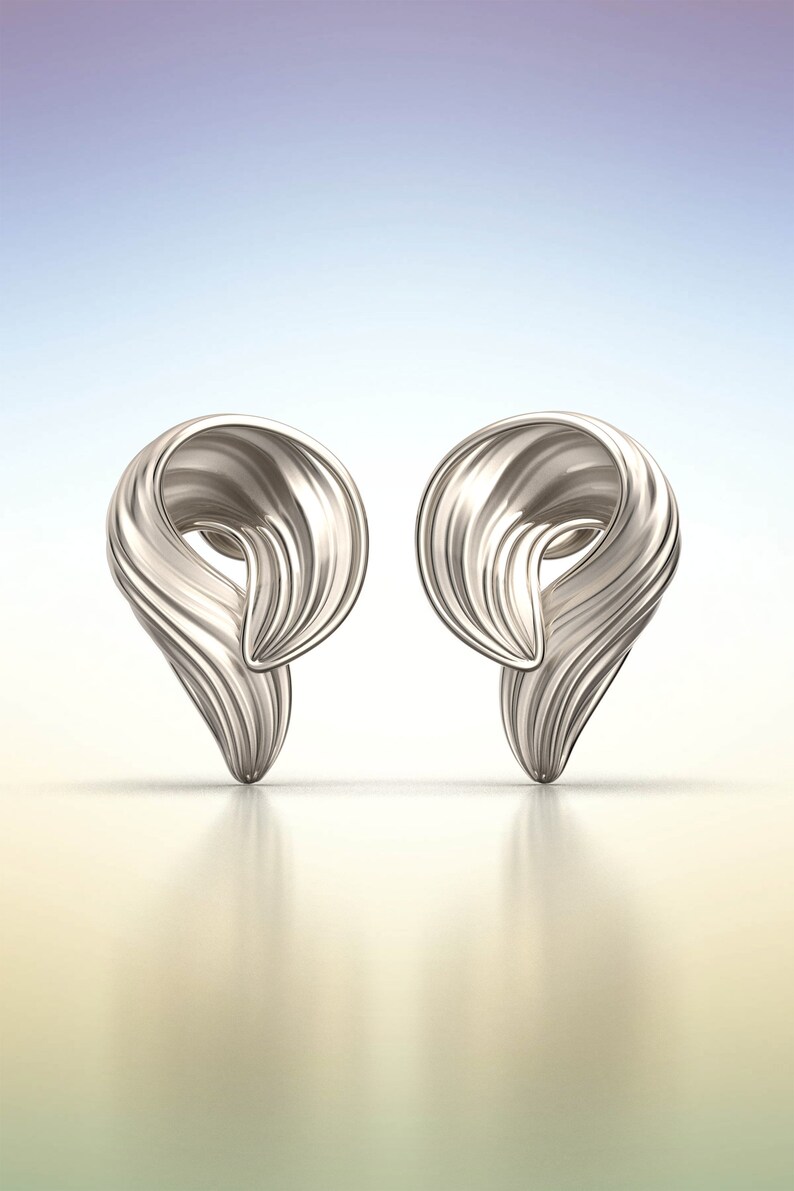 Puede incluir: Un par de pendientes de plata con un dise&ntilde;o &uacute;nico y abstracto. Los pendientes tienen forma de remolino o ola, y tienen un acabado liso y pulido.