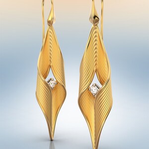 Puede incluir: Un par de pendientes de oro con un diamante en el centro de cada uno. Los pendientes tienen forma de hoja y una superficie texturizada.
