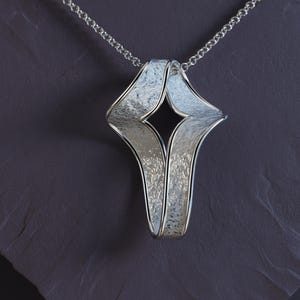 Elegant twisted gold cross pendant lying next to a 45 cm Rolo chain