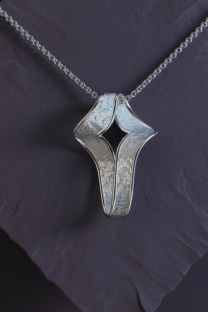 Elegant twisted gold cross pendant lying next to a 45 cm Rolo chain