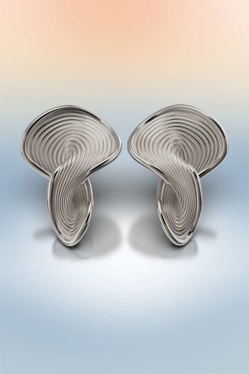 May include: A pair of silver earrings with a swirling, abstract design. The earrings are made of a smooth, shiny metal and have a modern, geometric look.