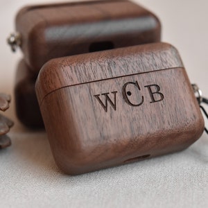 May include: A dark brown wooden case with a carabiner clip and the initials "WCB" engraved on the top. The case is made of walnut wood and has a sleek, modern design.