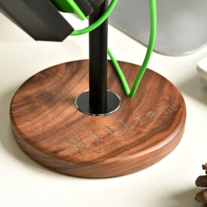 May include: A wooden headphone stand with a black metal pole and a circular base. The base is engraved with the name "William".