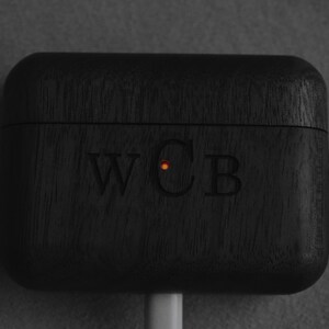 May include: Black wooden case with a carabiner clip and the initials "WCB" engraved on the front. A small orange light is visible on the case.