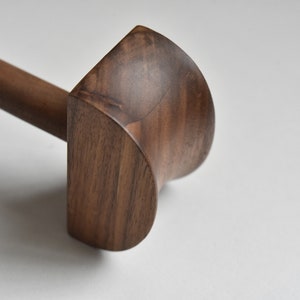 May include: A wooden mallet with a rounded head, made from dark brown walnut wood.