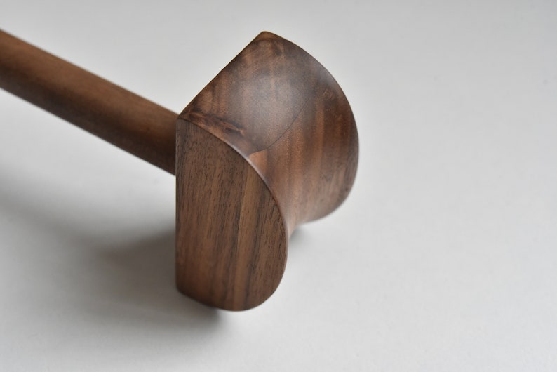 May include: A wooden mallet with a rounded head, made from dark brown walnut wood.