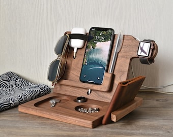 May include: A wooden organizer with slots for a phone, watch, and sunglasses. It also has a small tray for keys and a compartment for a wallet. The organizer is made of dark wood and has a natural finish.