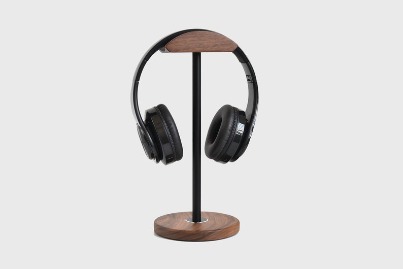 May include: A black headphone stand with a wooden base and a wooden top piece. The headphones are black with a black headband.