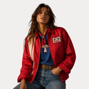 Peut inclure: Veste rouge avec des rayures blanches sur les manches et un écusson "GT-1 Kendall". L'ensemble comprend un t-shirt bleu, un jean et une ceinture marron. Un bandana rouge est porté autour du cou.