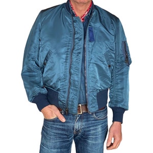 Può includere: Una giacca bomber blu con chiusura a zip e collo e polsini a costine.