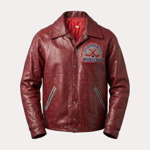 May include: A burgundy leather jacket with a button-up front, a collar, and a red quilted lining. The jacket features a patch on the chest that reads "Emergency Hockey Club" with crossed hockey sticks.