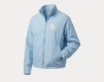 May include: A light blue jacket with a full zipper closure, a stand-up collar, and long sleeves. The jacket features a white embroidered logo on the left chest. The jacket has two front pockets and a light blue lining.