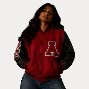 May include: A red varsity jacket with black leather sleeves. The jacket features a large white "A" on the chest and sports-themed patches on the left sleeve. The jacket has a button-up front and pockets.