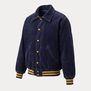 Puede incluir: Chaqueta bomber de pana azul marino con cierre de botones y cuello clásico. La chaqueta presenta detalles amarillos en los puños y el dobladillo, y botones amarillos. Una prenda de abrigo elegante.