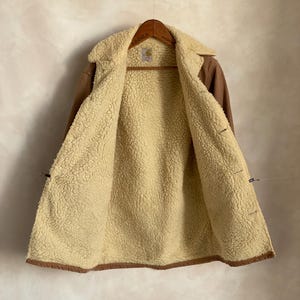 May include: A brown corduroy jacket with a sherpa lining. The jacket has a button closure and two pockets on the front.