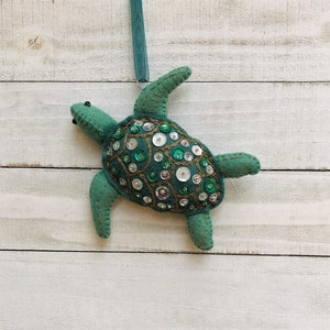 May include: A green felt sea turtle ornament with a shell decorated with sequins and beads.