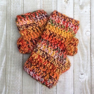 May include: A pair of crocheted fingerless gloves in a multi-colored yarn with shades of orange, yellow, red, and pink.