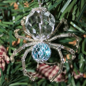 May include: A silver beaded spider ornament with a clear crystal body and a blue crystal abdomen.