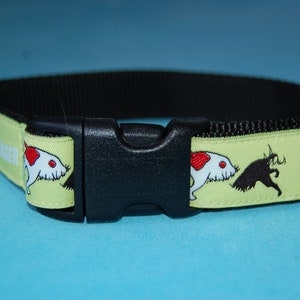 Könnte beinhalten: Hundehalsband mit schwarzer Schnalle und hellgrünem Riemen. Der Riemen zeigt ein sich wiederholendes Muster einer weißen Maus mit rotem Fleck und einer schwarzen Maus-Silhouette. Das Wort "MAUSER" ist ebenfalls sichtbar.