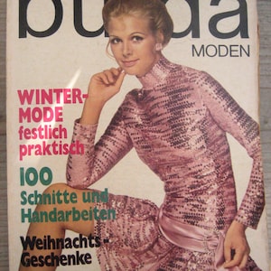 Peut inclure: Une couverture de magazine vintage avec une femme portant une robe à paillettes roses. Le titre du magazine "buda MODEN" est en haut, avec du texte en allemand en dessous. La couverture présente également le texte "WINTER MODE festlich praktisch 100 Schnitte und Handarbeiten Weihnachts Geschenke 11 NOVEMBER 1965".