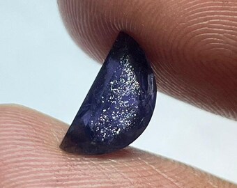 May include: A half-moon shaped gemstone with a dark blue color and a sparkly, iridescent finish.