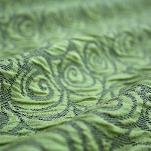 Peut inclure: Tissu vert avec un motif texturé en spirale. Le tissu a un léger brillant et une sensation douce et fluide.