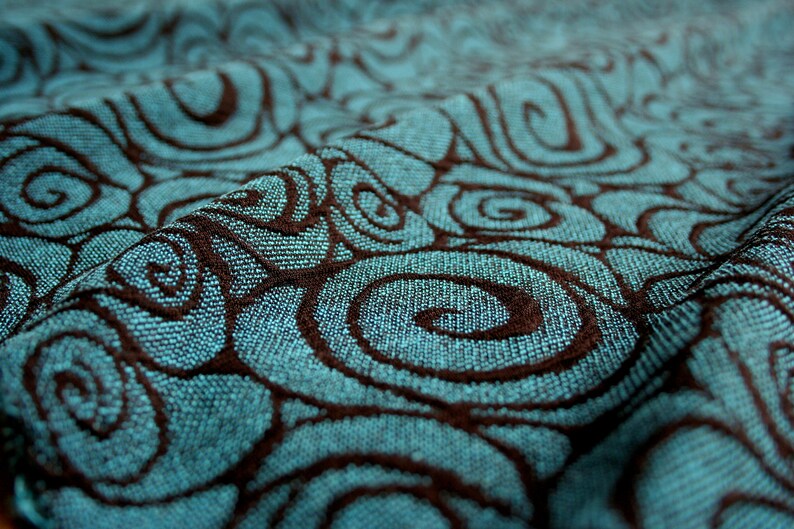 May include: Close-up of a teal fabric with a brown swirl pattern. The fabric is textured and has a soft, woven look.