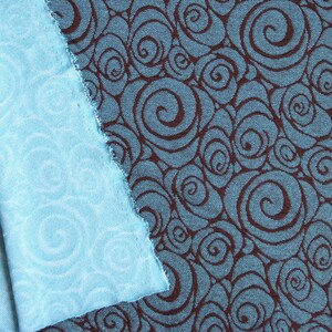 May include: Two pieces of fabric with a swirling pattern. One piece is a light blue fabric with a white swirl pattern. The other piece is a dark blue fabric with a brown swirl pattern.