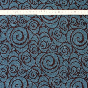 May include: Teal fabric with a brown swirl pattern. The fabric has a textured surface.