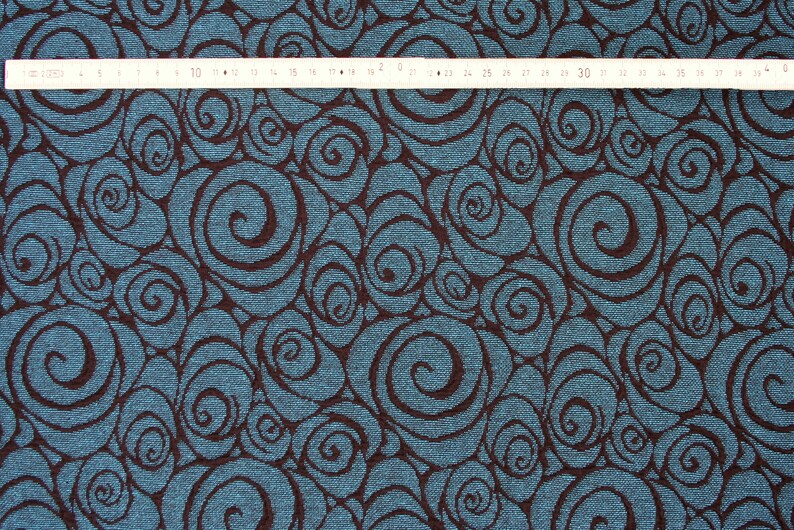 May include: Teal fabric with a brown swirl pattern. The fabric has a textured surface.