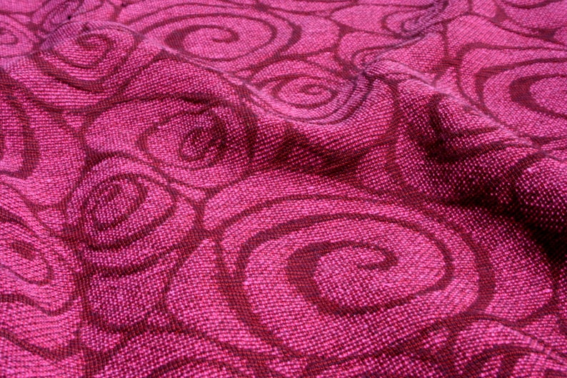 Peut inclure: Gros plan sur un tissu textur&eacute; dans des tons magenta et bordeaux fonc&eacute;. Le tissu pr&eacute;sente un motif r&eacute;p&eacute;titif de motifs tourbillonnants en spirale. Le tissage du tissu est visible, ajoutant de la profondeur et de la texture &agrave; l'aspect g&eacute;n&eacute;ral.