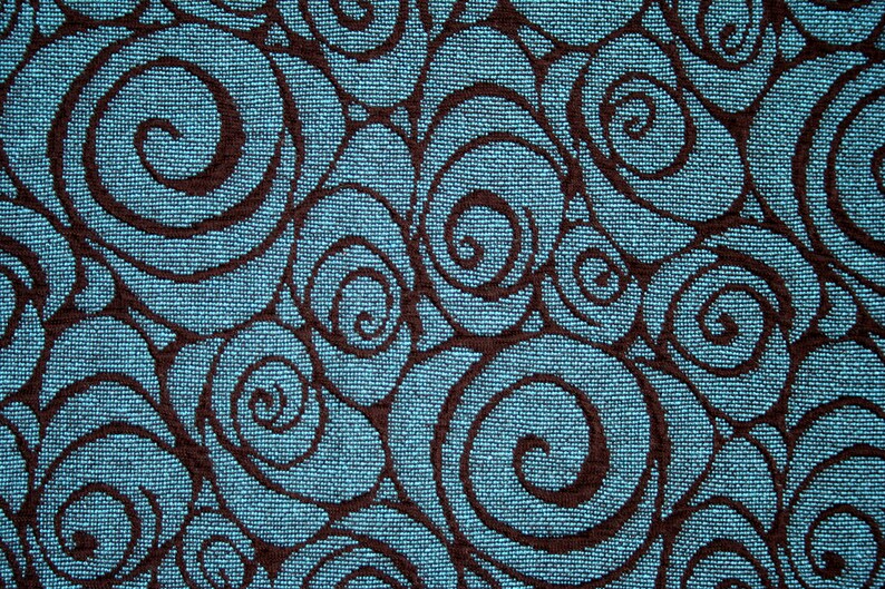 May include: A blue fabric with a repeating pattern of brown swirls. The swirls are stylized to look like roses.