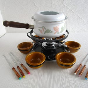 Könnte beinhalten: Eine weiße Keramik-Tasse mit schwarzem Henkel und dem Text "But First, Coffee" in schwarzer, handschriftlicher Schrift. Die Tasse steht auf einer weißen Oberfläche.