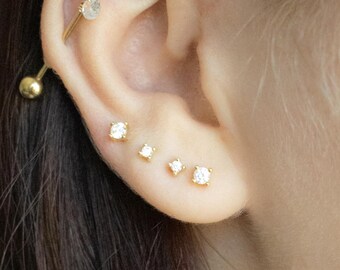 Puede incluir: Una persona con cabello largo y oscuro que lleva varios pendientes de oro con pequeñas piedras preciosas transparentes. Los pendientes están en los piercings de hélice, lóbulo y hélice delantera.
