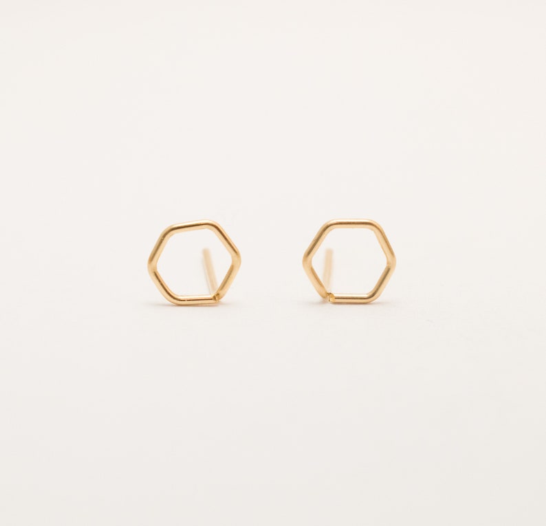 Pu&ograve; includere: Un paio di orecchini a bottone esagonali in oro. Gli orecchini sono semplici e minimalisti, e sarebbero un ottimo regalo per chi ama i gioielli geometrici.