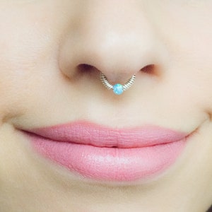 Könnte beinhalten: Nahaufnahme einer Nase mit einem silbernen Septumring mit einem blauen Opal-Edelstein.