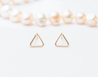 Puede incluir: Un par de pendientes de triángulo de oro. Los pendientes son simples y minimalistas, y serían un gran regalo para alguien que ama la joyería geométrica.