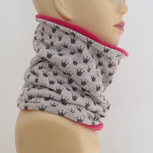 Può includere: Scaldacollo grigio con un motivo a corona nera e una fodera in pile rosa.