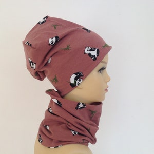 Könnte beinhalten: Eine rosa Mütze und ein passender Halsschmuck mit Panda- und Bambusdruck.
