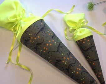 Può includere: Due sacchetti a forma di cono a tema dinosauri. Le borse hanno uno sfondo verde scuro con scheletri di dinosauri, impronte e ossa in arancione e giallo. Le parti superiori sono giallo brillante e legate con nastri gialli.