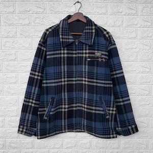 May include: A blue, black, and white plaid jacket with a zipper closure. The jacket has two pockets on the front and a small patch with the text "Denim & Supply" on the right side.