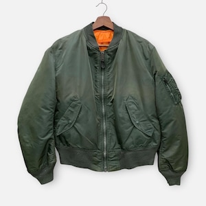May include: Olive green bomber jacket with a full-length zipper, two front pockets, and a zippered pocket on the left sleeve. The jacket has a ribbed collar, cuffs, and hem. The interior lining is bright orange.