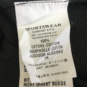 May include: A white clothing tag with black text, featuring the brand name "SPORTSWEAR" and details about the company's location in Italy. The tag also lists the fabric composition as 100% cotton and includes care instructions.