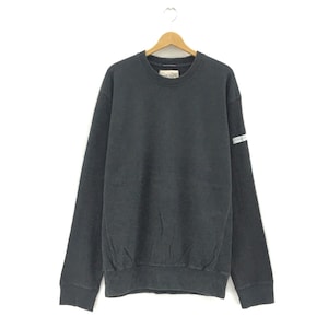 May include: A dark gray sweatshirt with a crew neck and long sleeves, hanging on a wooden hanger. The sweatshirt has a small tag on the upper chest and a reflective stripe detail on the left sleeve. The fabric appears to be a soft, comfortable material.