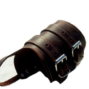 Op de afbeelding: Bruin leren armband met twee zilveren gespen.